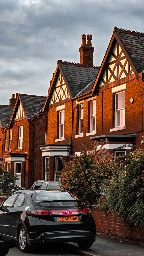 Row of traditional English townhouses with a black car parked on a serene street.