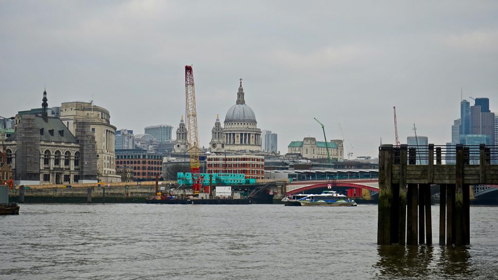 Cityscape of London featuring St. Paul's Cathedral and the River Thames on a cloudy day.